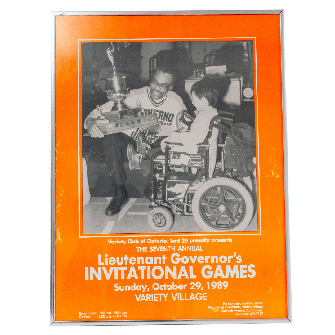 Photograph showing a picture of a man sitting and holding a trophy and a young boy in a wheelchair displayed in a frame.